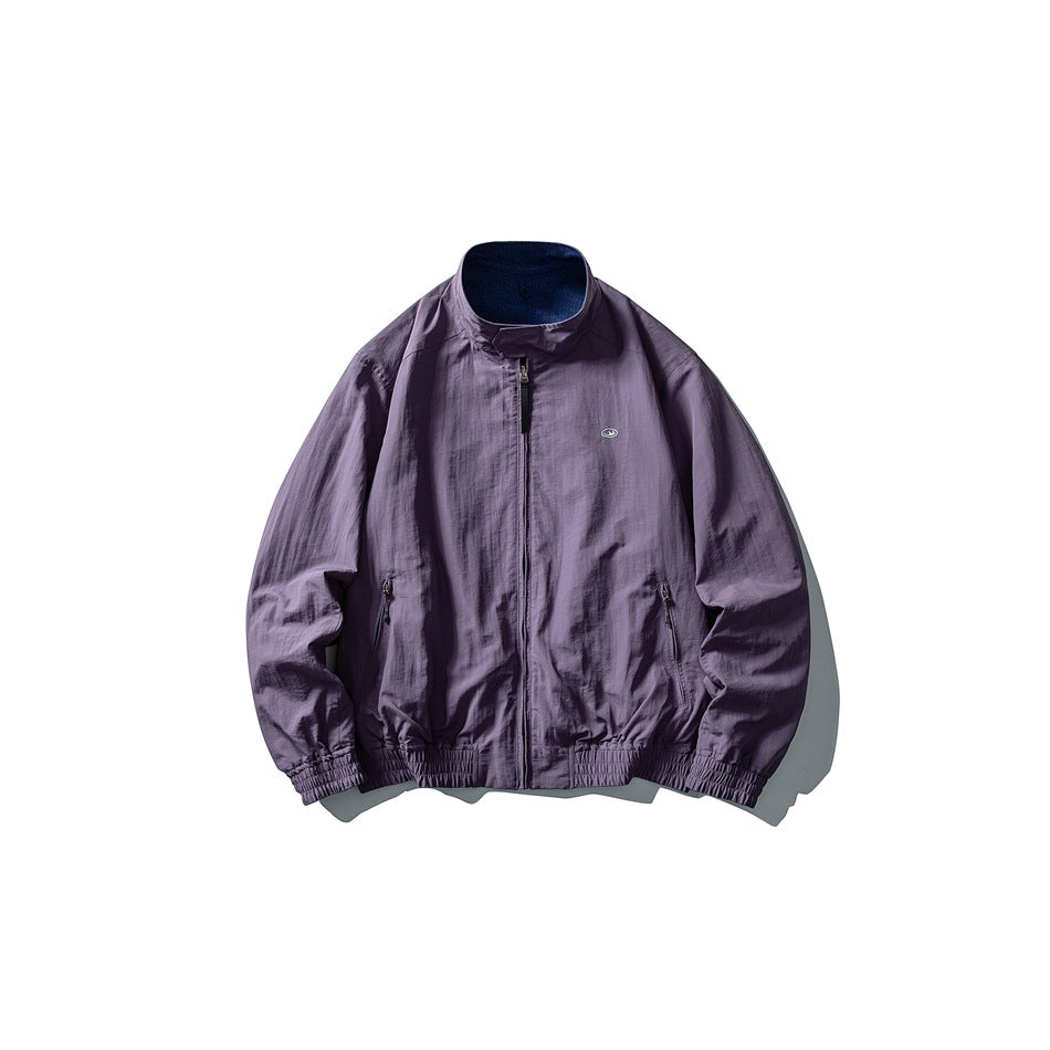 Front view of a muted purple zip-front jacket with a stand collar, two zip pockets, and elasticated cuffs and hem.