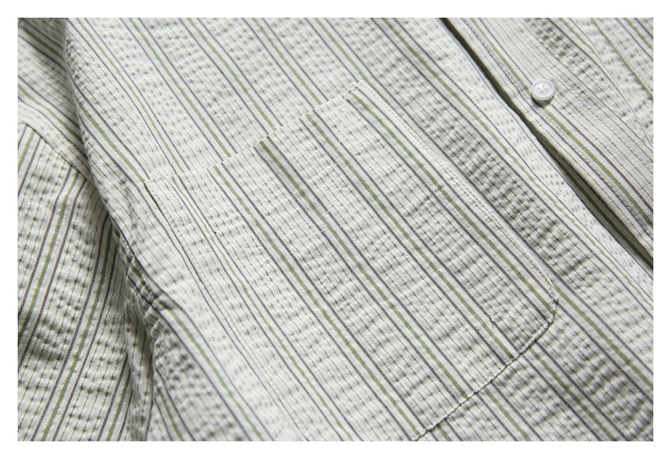 Close-up of a rectangular chest pocket on an off-white shirt with narrow gray and muted green stripes.