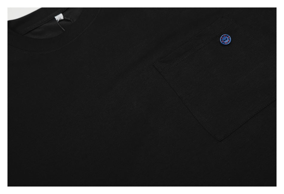 Close-up of a black shirt with a chest pocket and a small blue button with red accents.