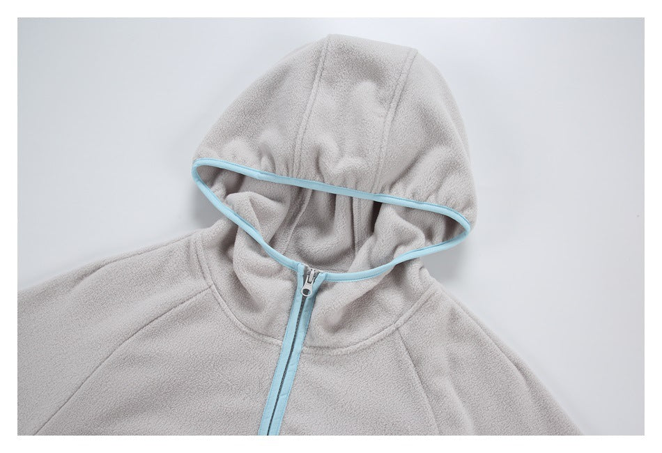Close-up of a light gray jacket's hood and upper front, showing pale blue edging and a front zipper.
