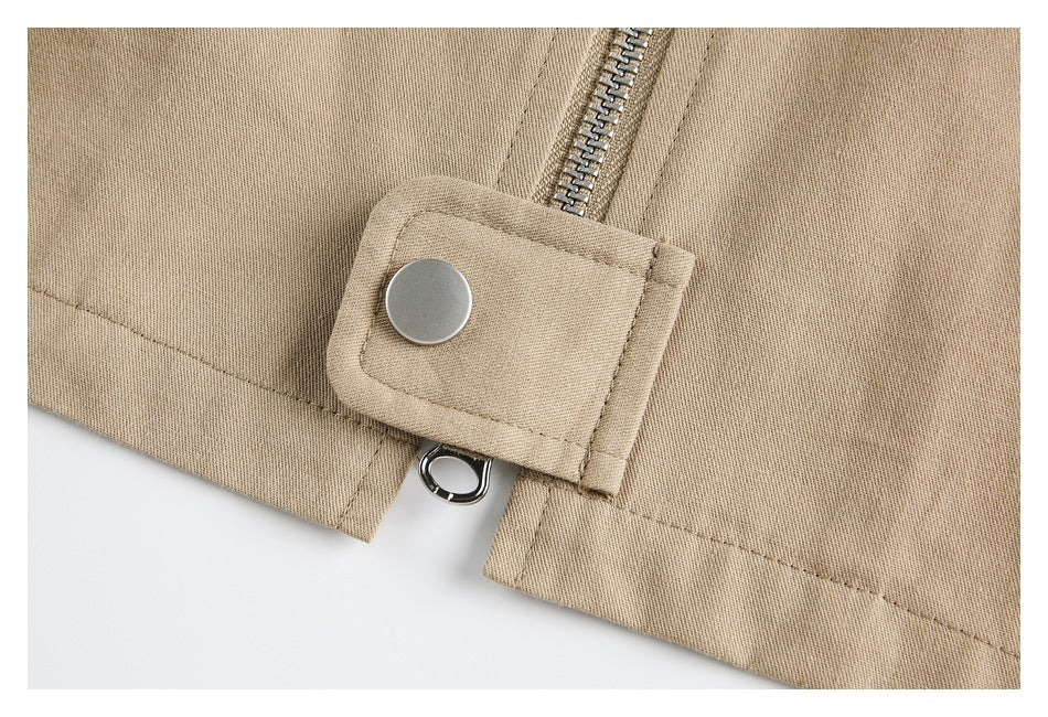 Close-up of a tan jacket's zipper-end snap tab and metal eyelet.