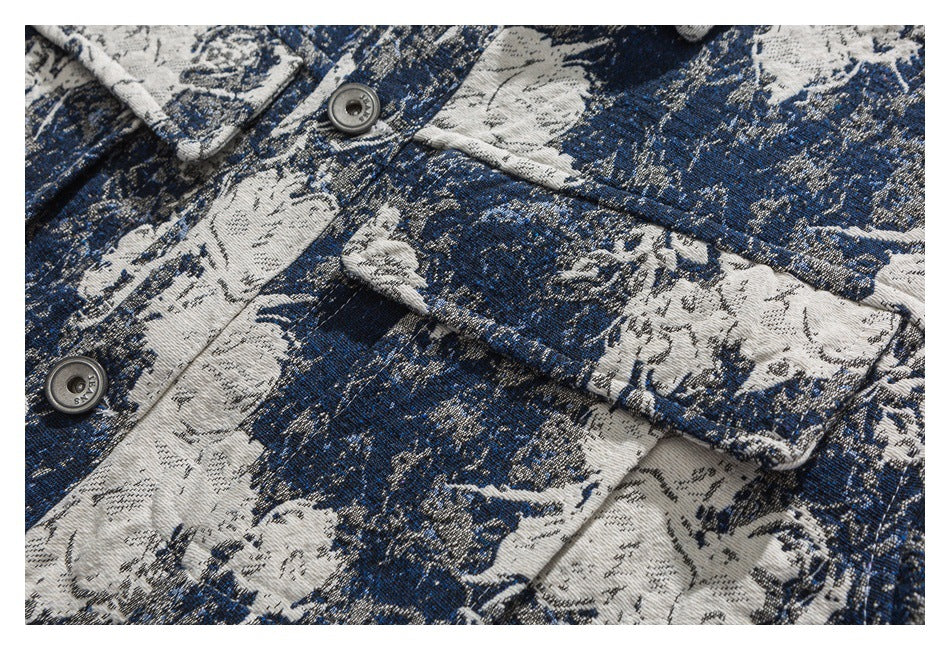 Close-up of a blue and ivory floral-patterned garment showing a button, pocket flap and stitching.
