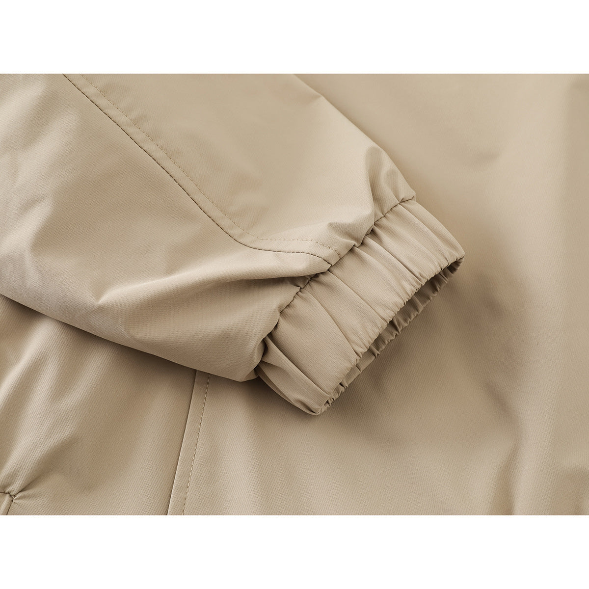 Close-up of a beige jacket sleeve with a gathered elastic cuff and visible stitching.