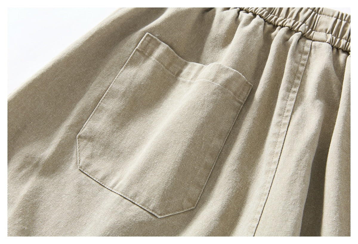 Close-up of beige pants showing a large patch pocket and gathered elastic waistband.