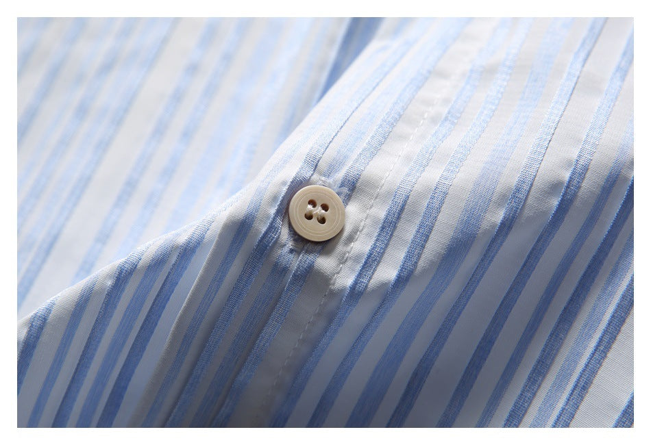 Close-up of a white shirt with narrow blue stripes and a beige button.