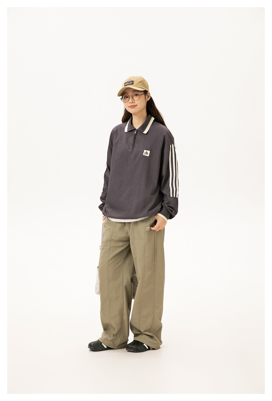 Model wears a charcoal oversized quarter-zip pullover with a cream-trimmed collar and three cream sleeve stripes.