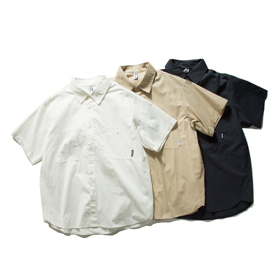 Three short-sleeve button-up shirts arranged together in white, beige and dark navy, shown from the front.