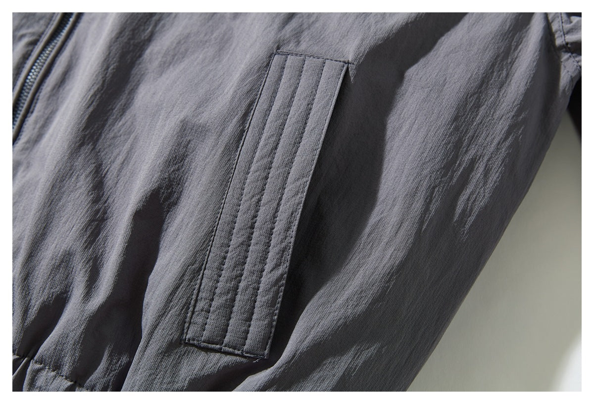 Close-up of a narrow stitched vertical detail on the charcoal gray jacket beside the front zipper.