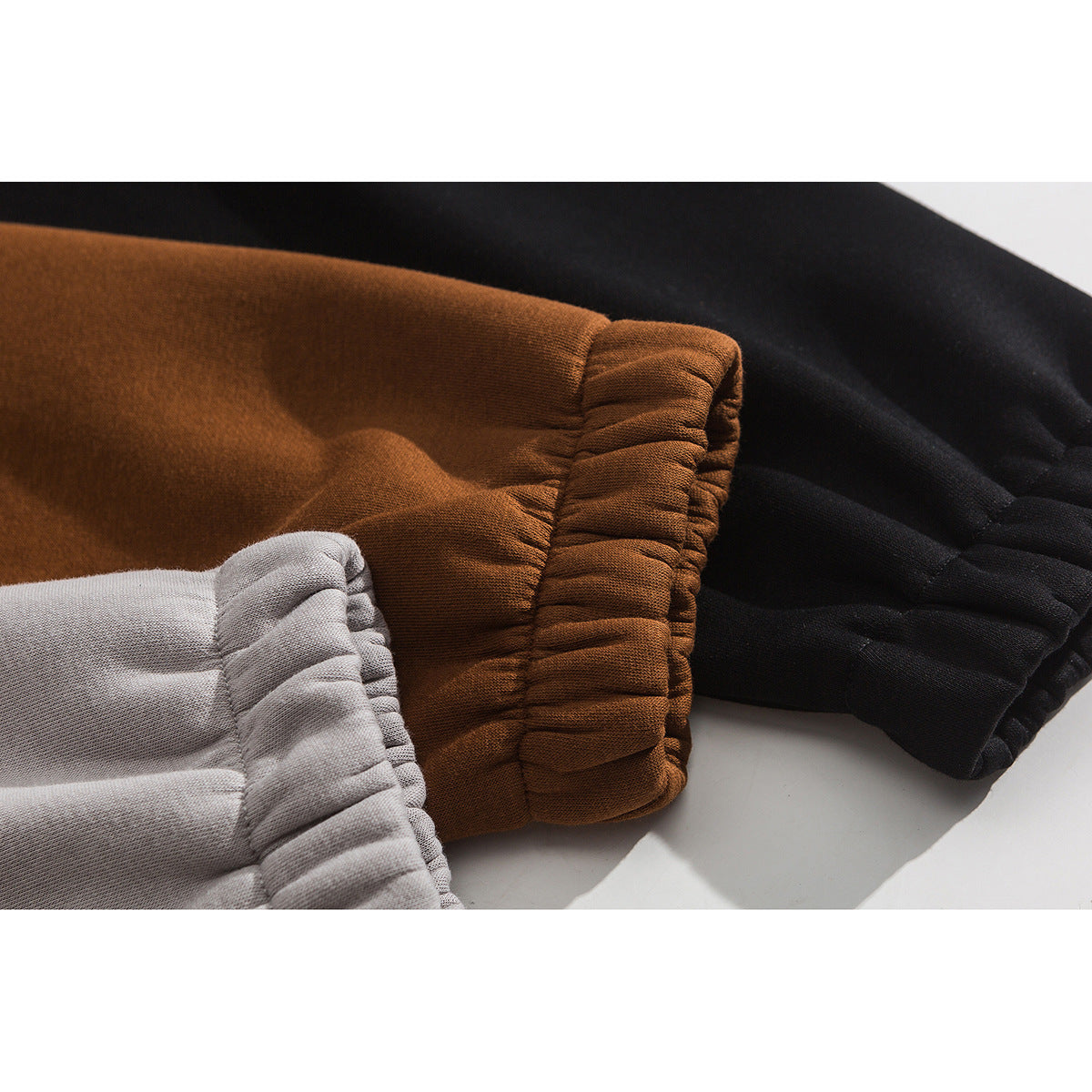 Close-up of gathered elastic cuffs on gray, rust-brown, and black jacket sleeves.