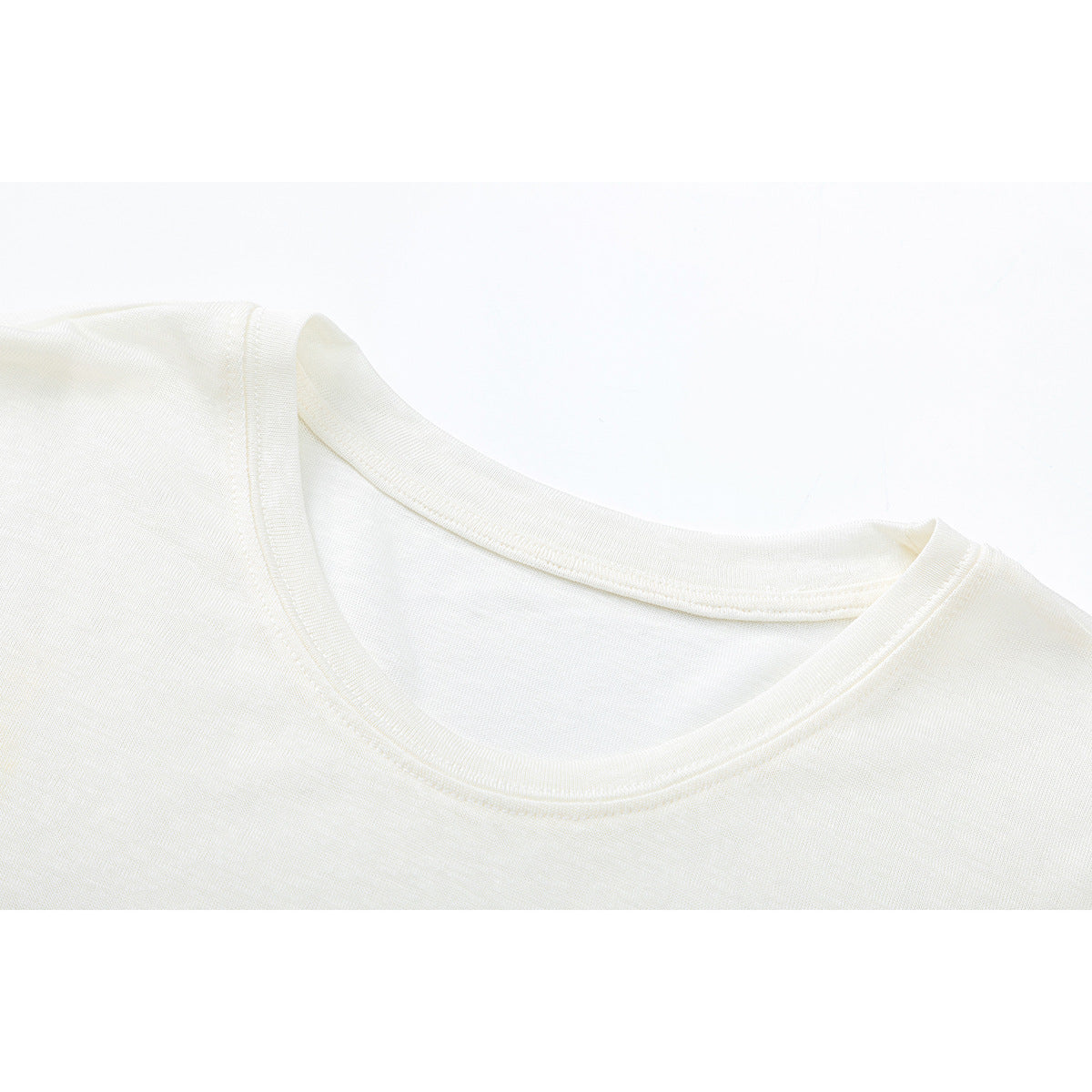 Close-up of an ivory T-shirt's crew neckline and shoulder seam.