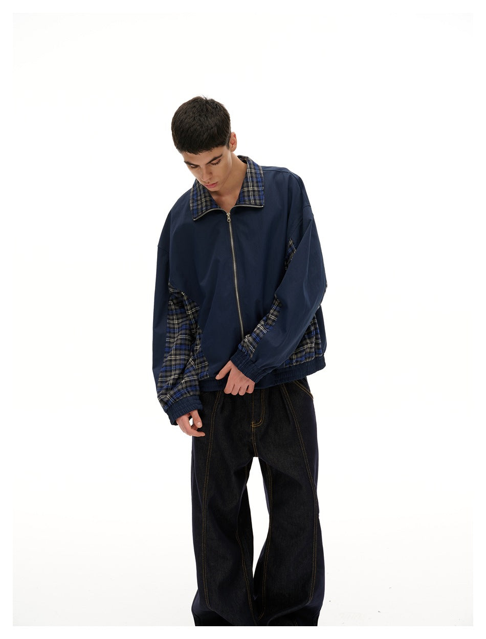 Closer view of a model wearing a navy zip-front jacket with a plaid collar and contrasting plaid sleeve and side panels.