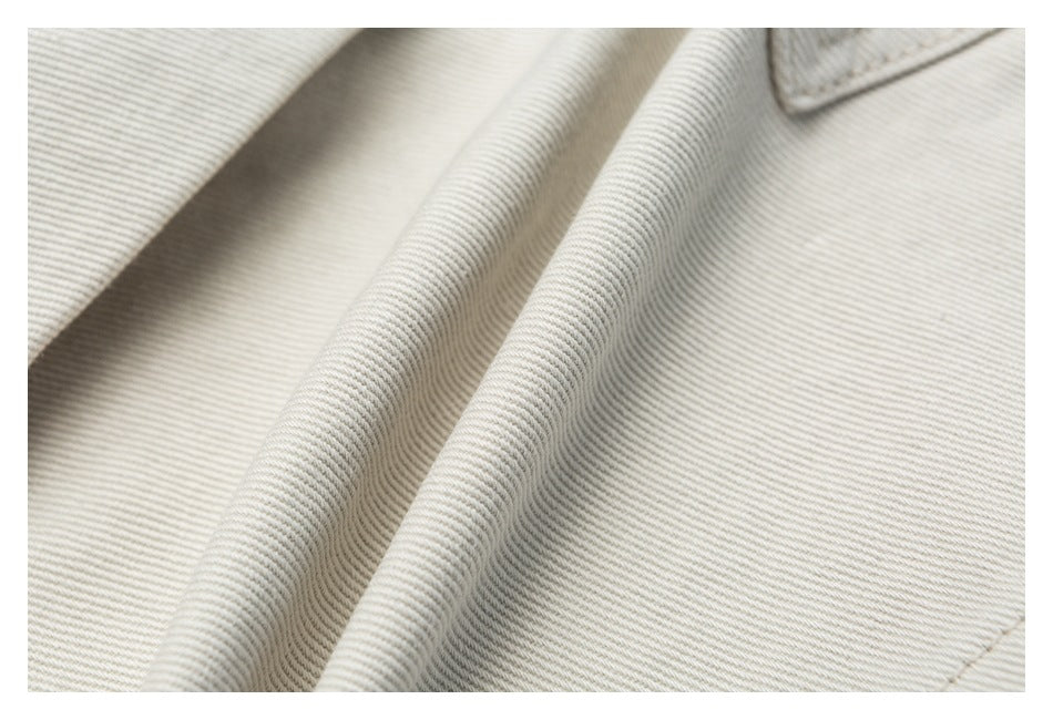 Extreme close-up showing the diagonal texture and folded drape of off-white trouser fabric.