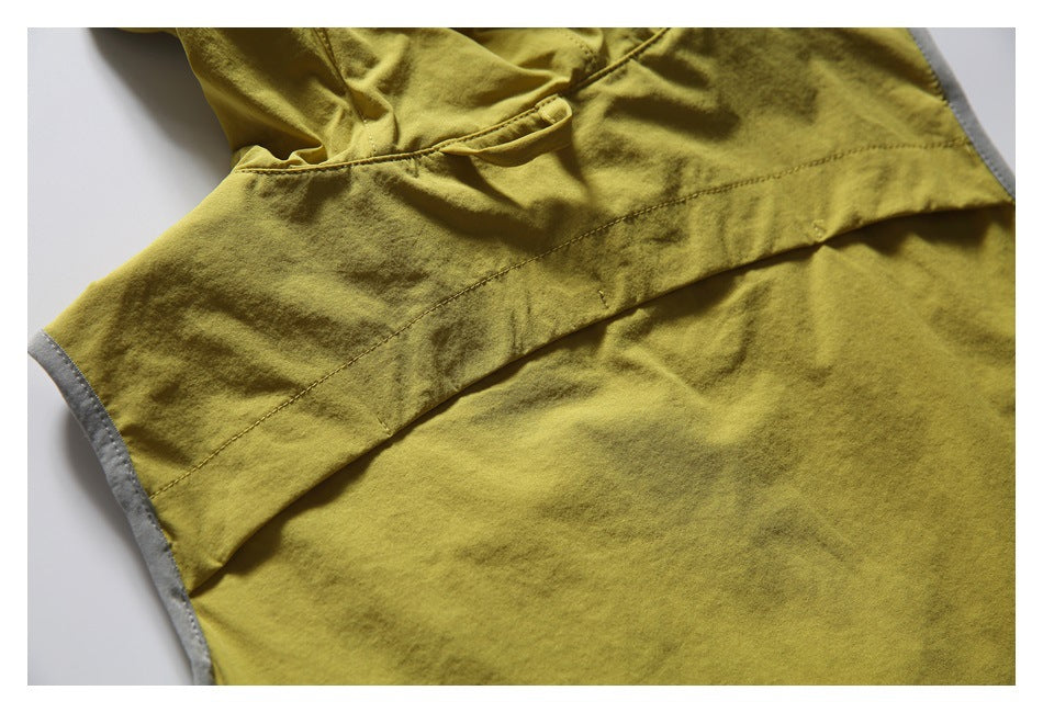 Close-up of a mustard-yellow garment panel showing curved seams and a small fabric tab.