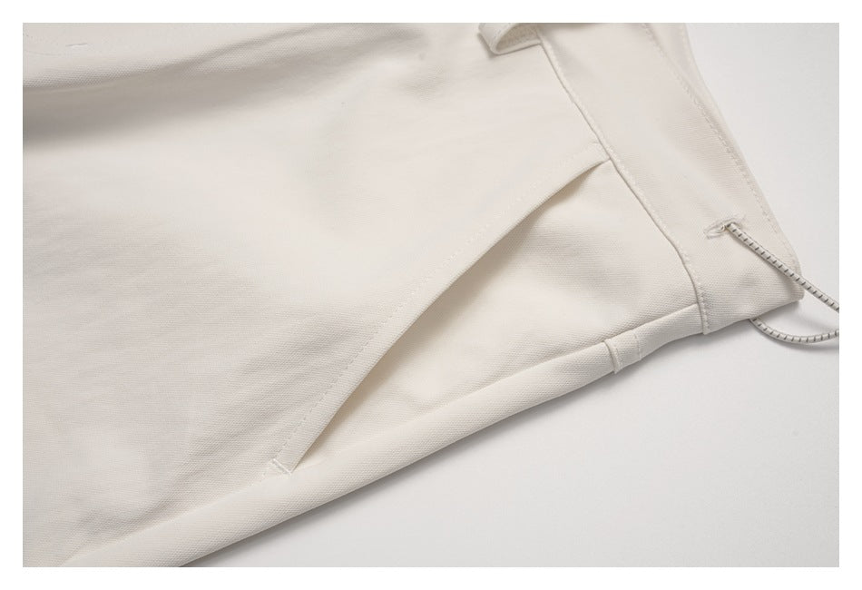 Close-up of a stitched side panel and seam on the ivory pants.