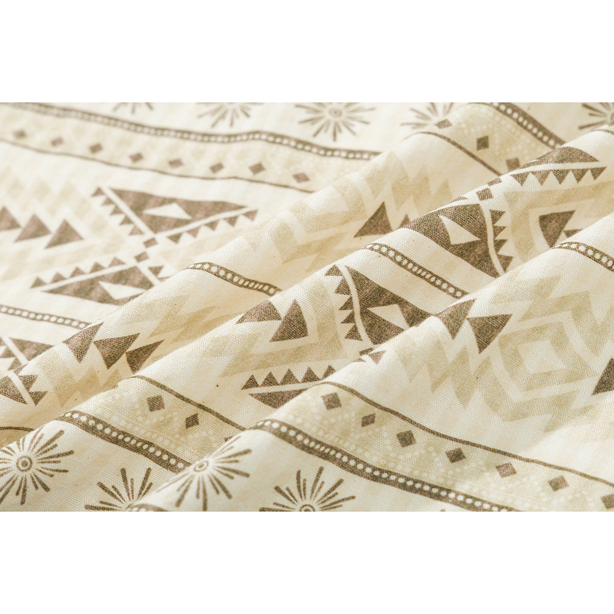 Close-up of cream fabric with repeating brown geometric shapes, sunbursts, and dotted stripes.