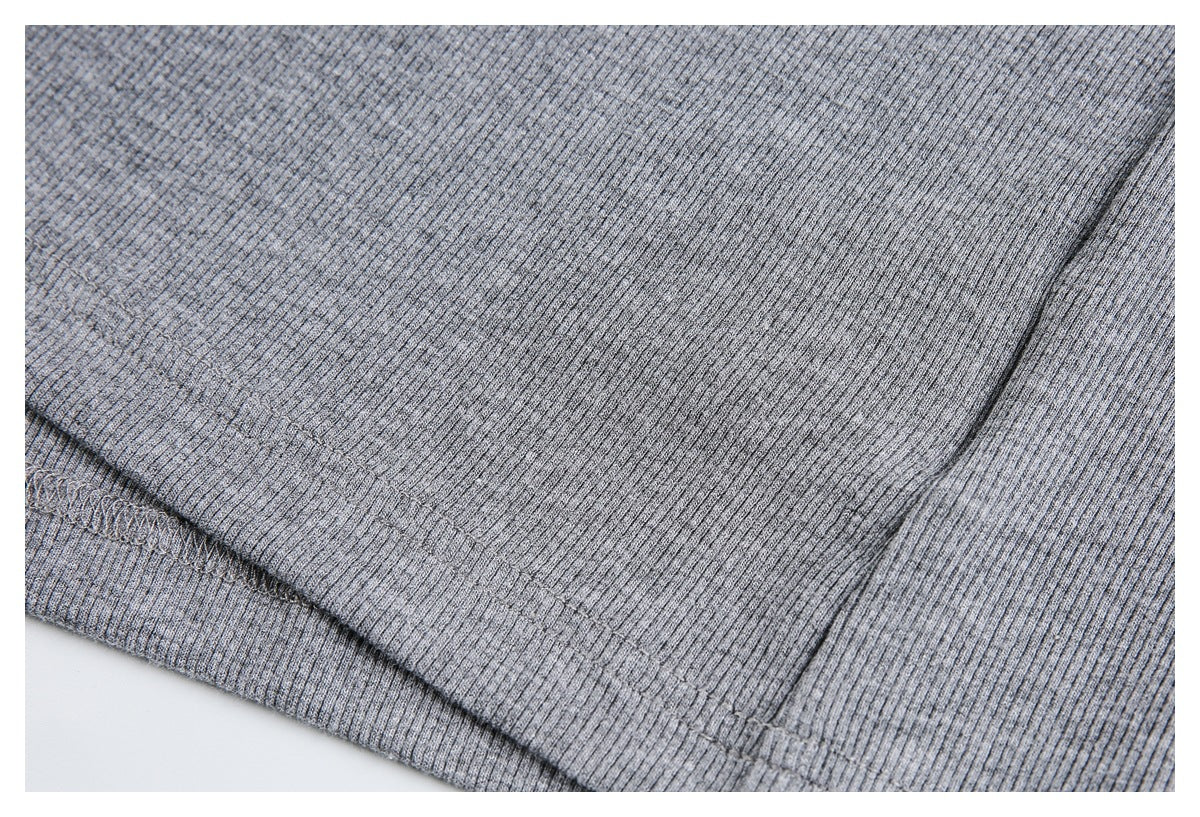 Close-up of gray ribbed fabric with a diagonal stitched seam and folded edge.
