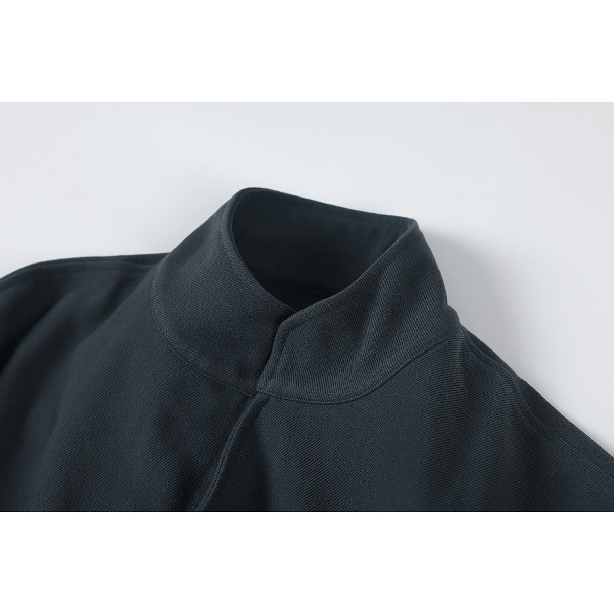 Close-up of a dark charcoal jacket's tall folded collar and upper shoulder.