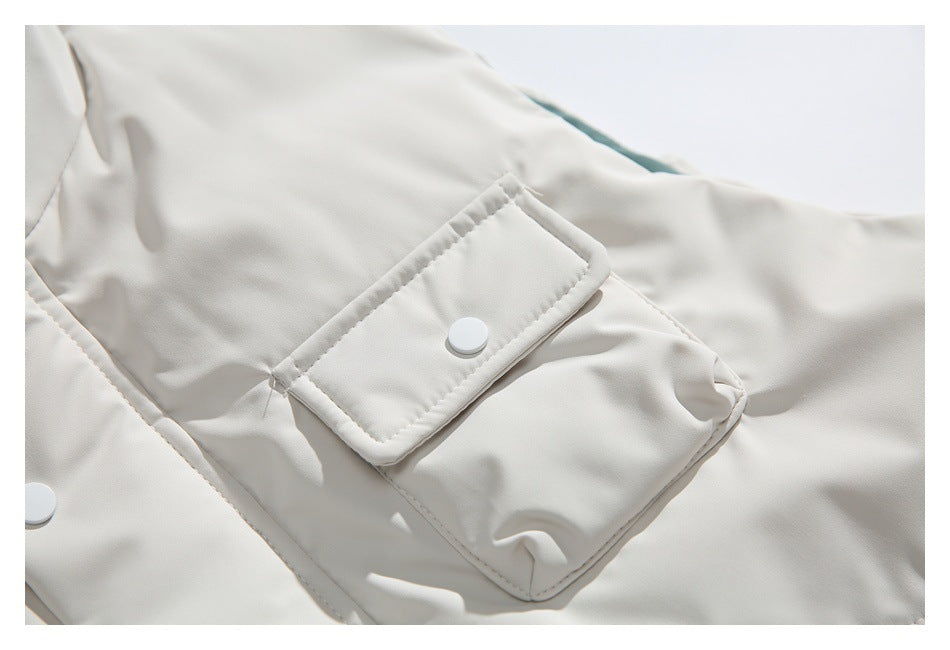 Close-up of an ivory vest flap pocket with a white snap button and visible stitching.