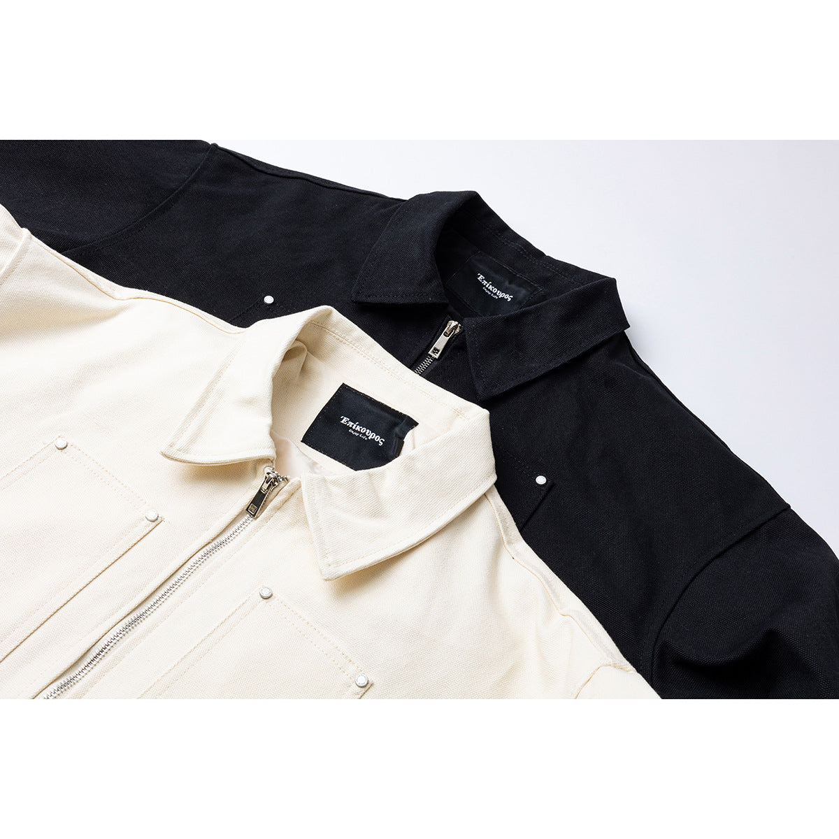 Close-up of black and ivory collared jackets with front zippers and snap details.