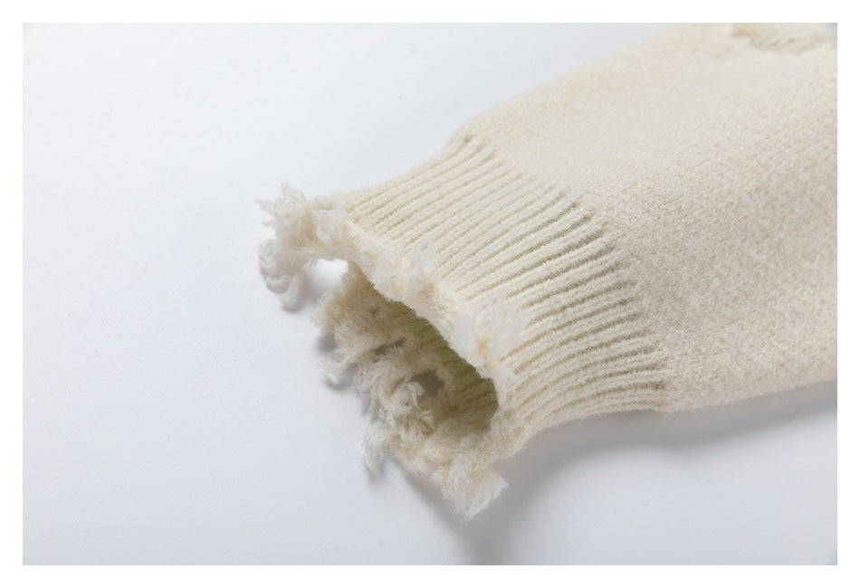 Close-up of an ivory sweater sleeve with a ribbed cuff and frayed edge.