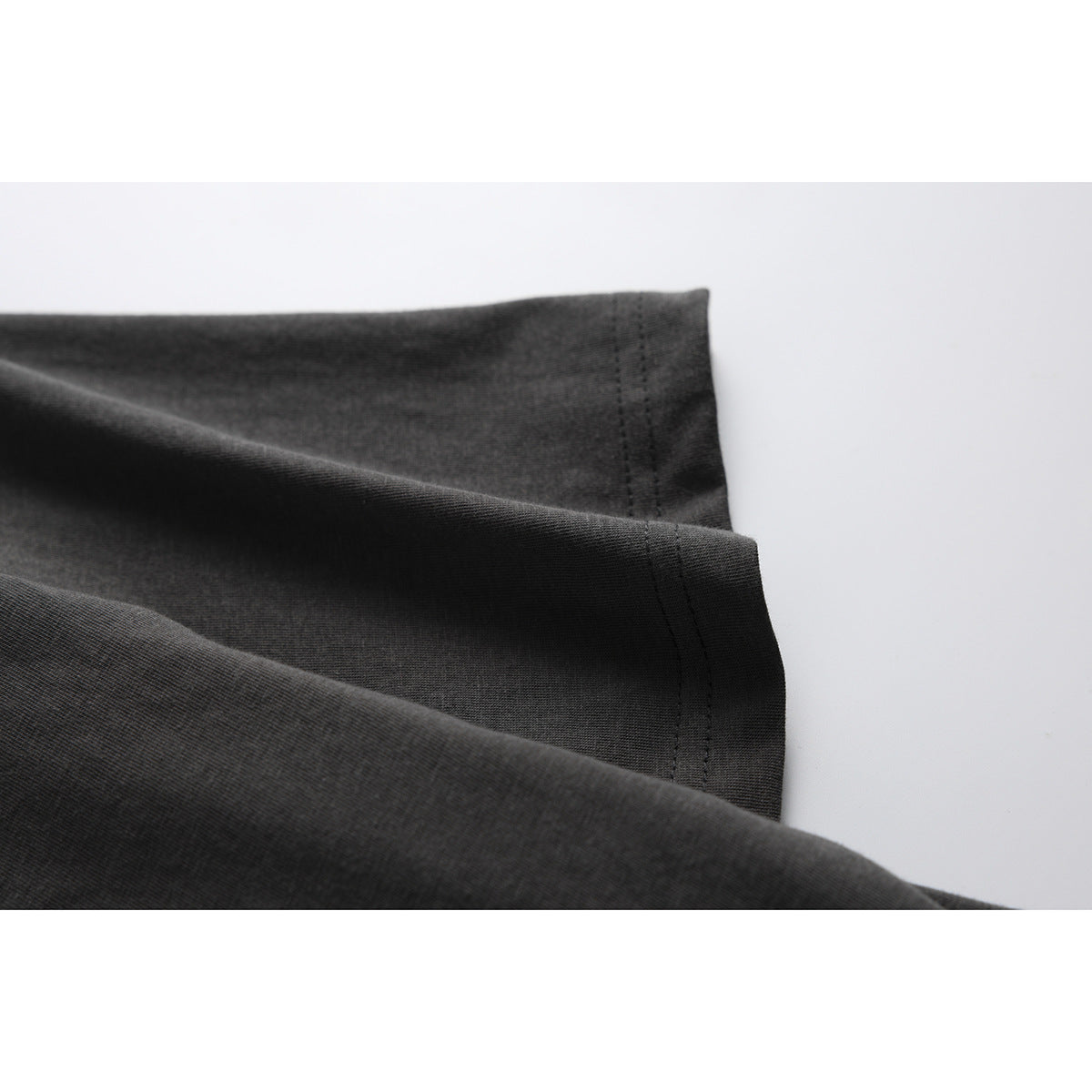 Close-up of the dark charcoal shirt fabric and double-stitched sleeve hem.