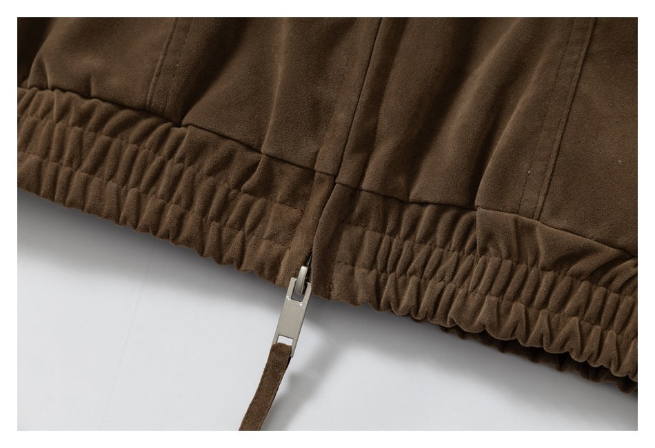 Close-up of a brown garment's gathered elastic hem and zipper pull.