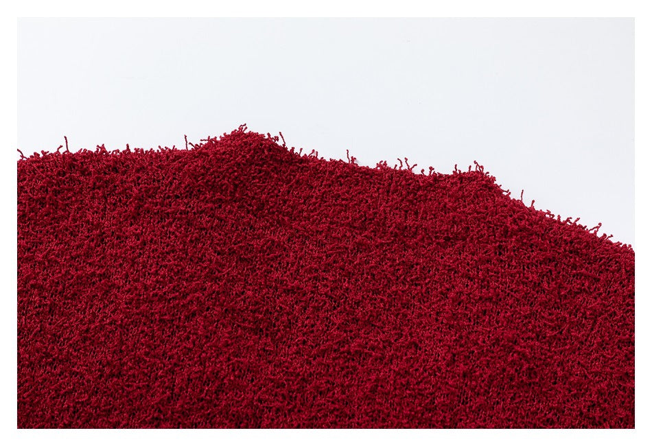 Close-up of deep red fuzzy knit fabric showing its uneven edge and dense looped texture.