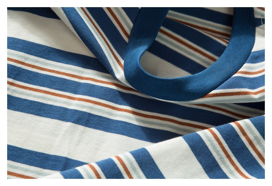 Close-up of a blue ribbed crew neckline on a striped garment in blue, cream, pale green, and rust.