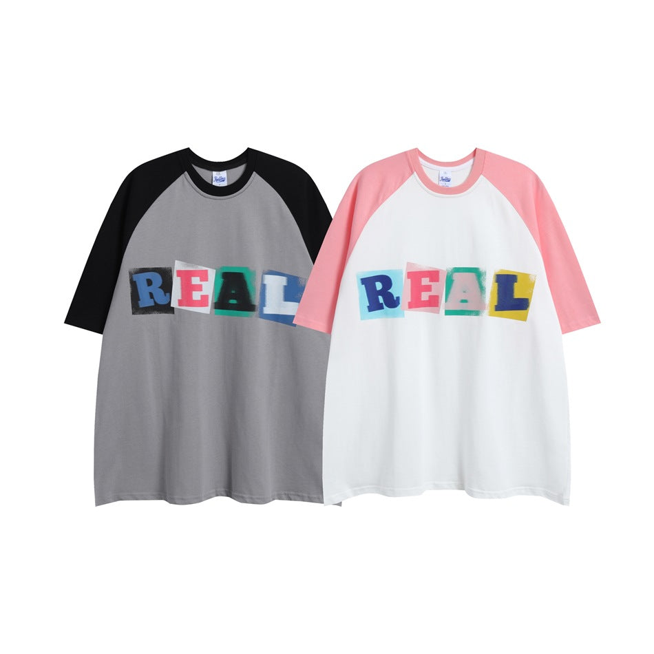 Two raglan T-shirts with colorful REAL lettering: one gray with black sleeves and one white with pink sleeves.