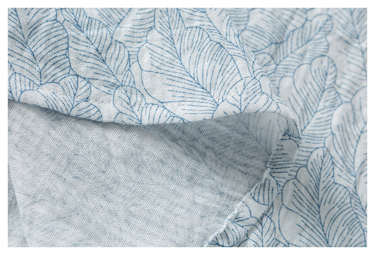 Close-up of blue leaf-print fabric folded over to reveal its plain, lightly textured reverse.