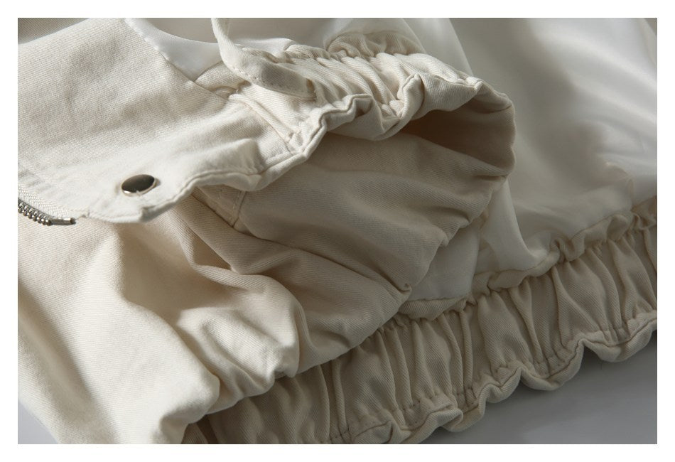 Close-up of a cream jacket with gathered elastic trim along the cuff and hem.