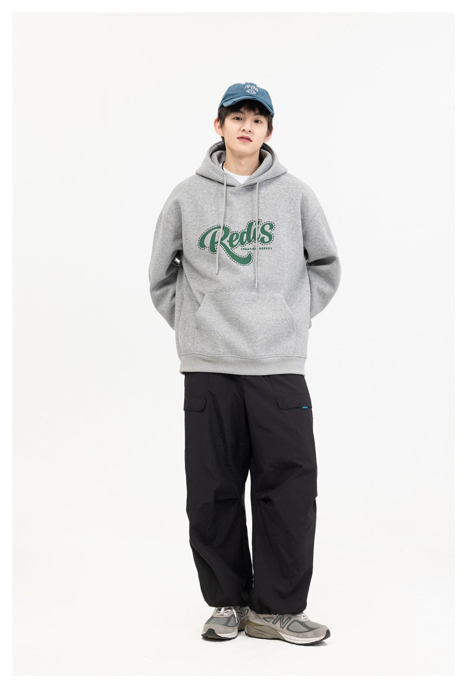 Front view of a model wearing a gray hoodie with a green chest graphic and black cargo pants.