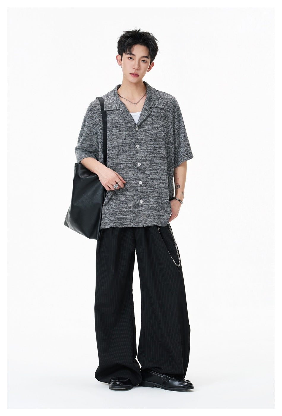 Model wearing a dark heather-gray short-sleeve button-up shirt with a wide collar and black trousers.