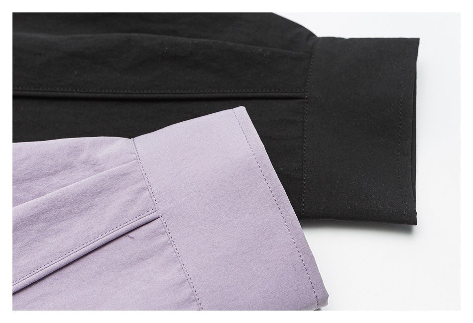 Close-up of shirt cuffs, showing a black cuff beside a pale lavender cuff.
