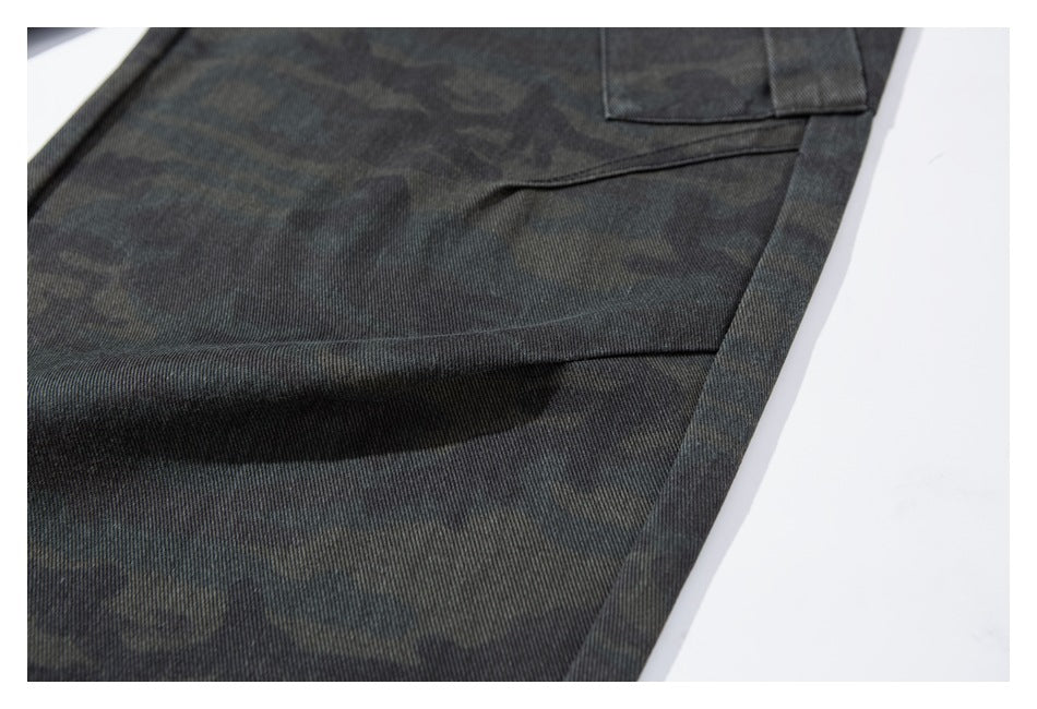 Close-up of dark camouflage trouser fabric, stitching, and a seam.