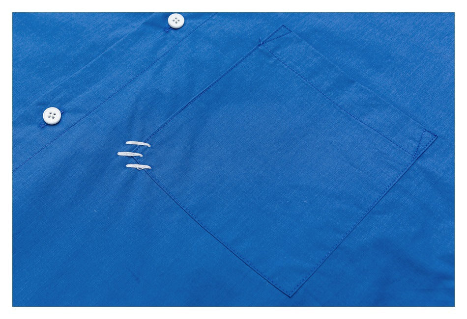 Close-up of a bright blue shirt's large chest pocket, white buttons, and short white stitch accents.
