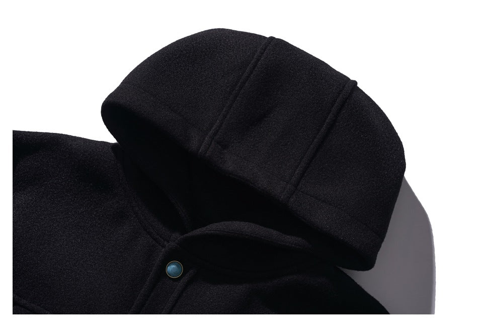 Close-up of a black coat’s hood, showing stitched panels and a metal snap at the neckline.