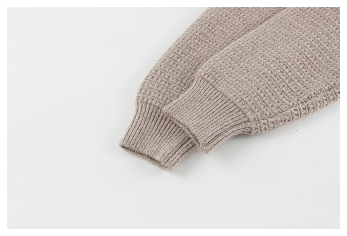 Close-up of a taupe textured cardigan sleeve ending in a ribbed cuff.