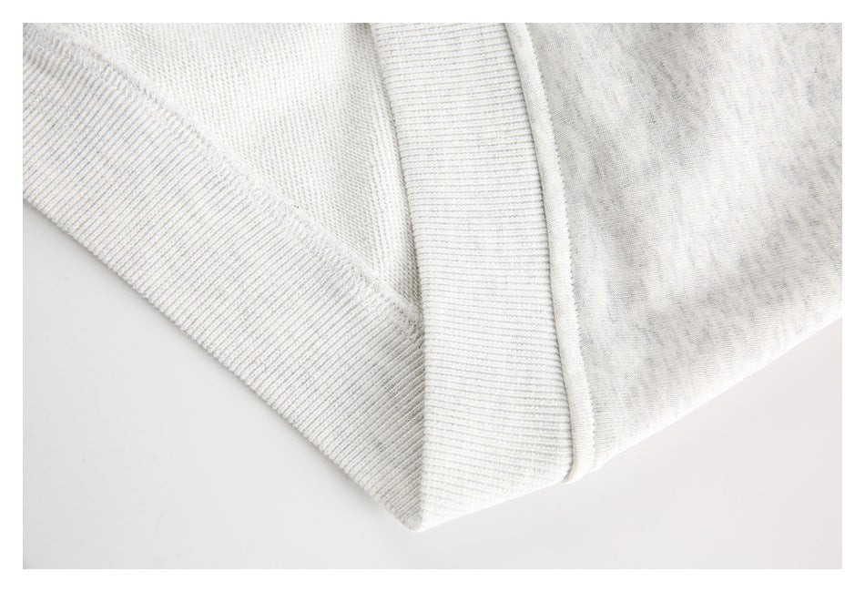 Close-up of ribbed sweatshirt trim and stitched seams in light gray heathered fabric.