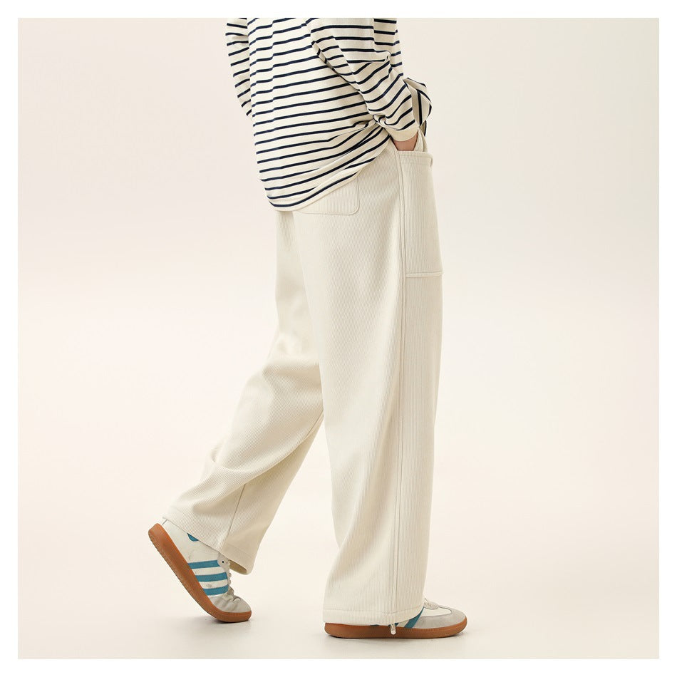 Side view of a model wearing wide-leg ivory ribbed pants with a side pocket and ankle zips.