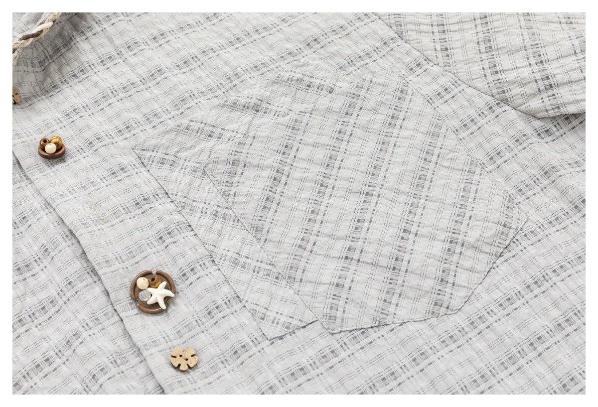 Close-up of a light gray checked shirt chest pocket and decorative buttons.