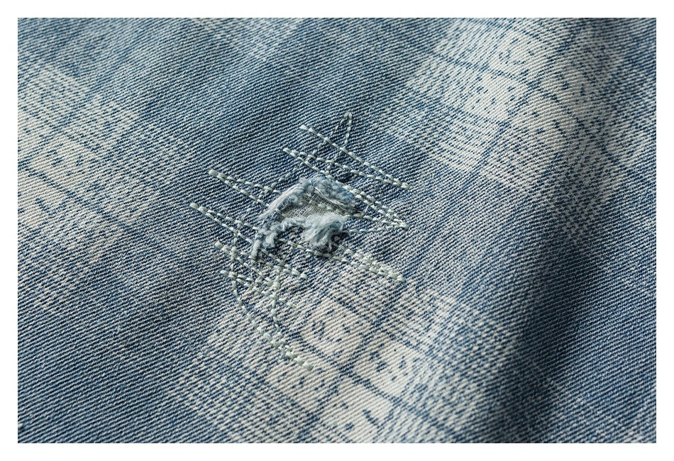 Close-up of blue-and-white patterned denim with a small frayed, stitched detail.