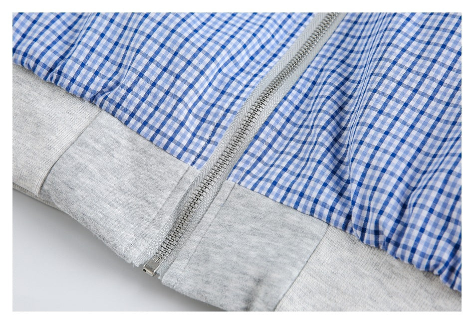 Close-up of a silver zipper and light gray hem on a blue-and-white gingham garment.
