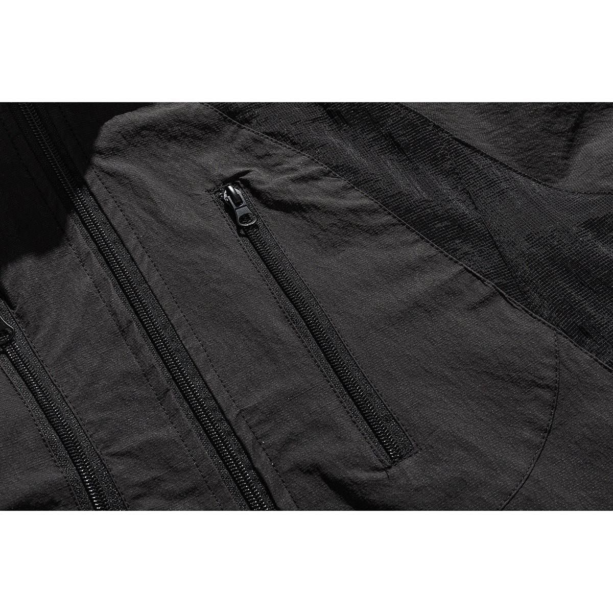 Close-up of the black jacket's chest area with a vertical zip pocket and textured paneling.