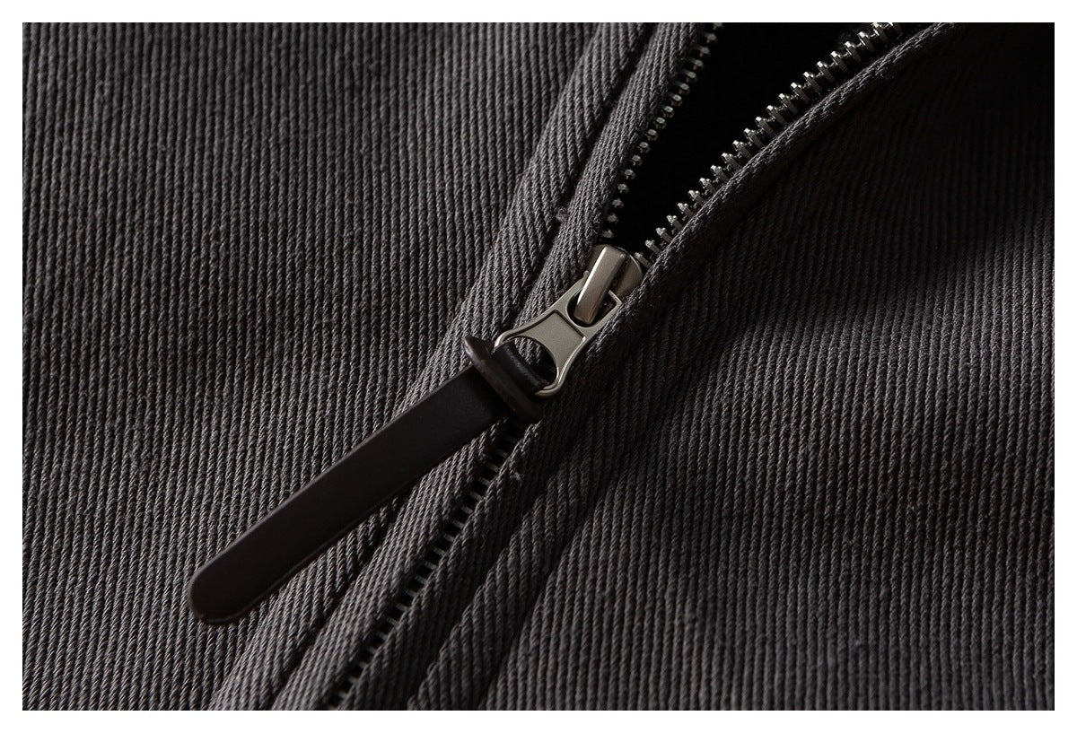 Close-up of a silver zipper slider and long dark pull on charcoal ribbed fabric.