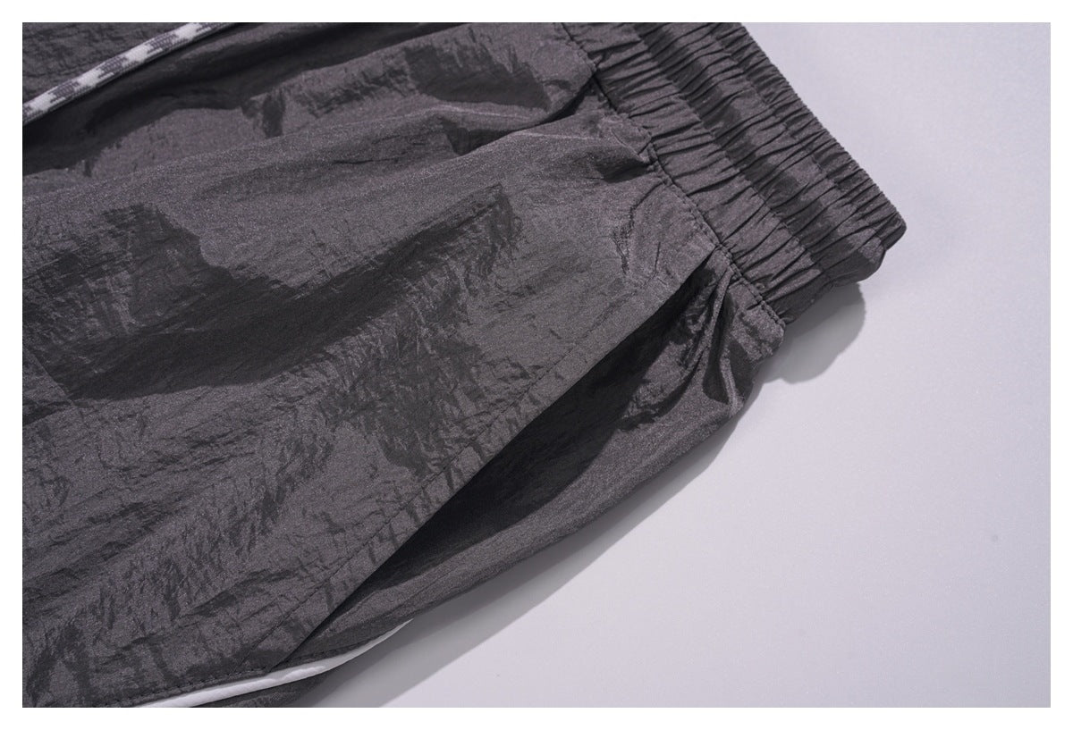 Close-up of the charcoal pants' elastic waistband, pocket seam, and white piping.