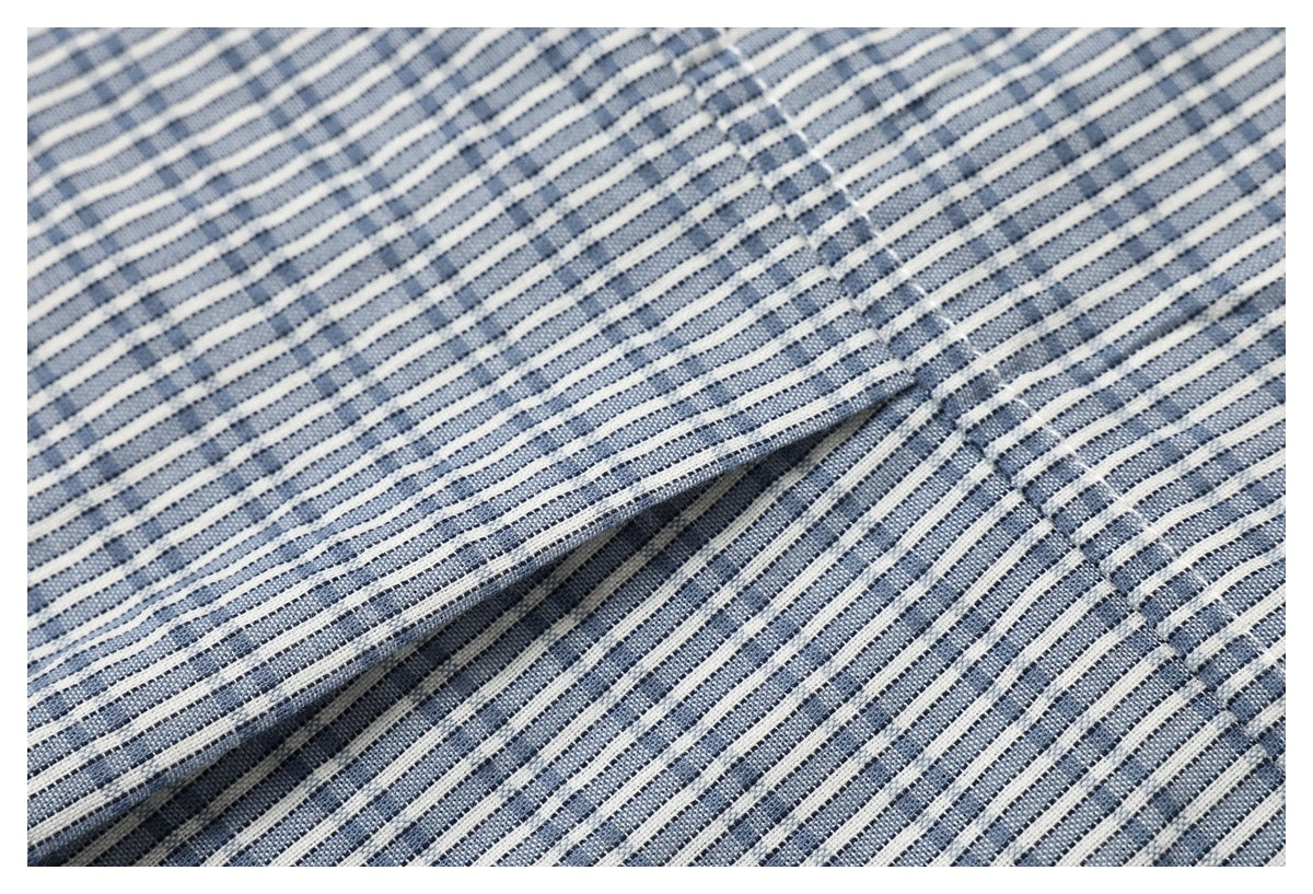 Close-up of stitching and a folded seam on blue-and-white striped garment fabric.
