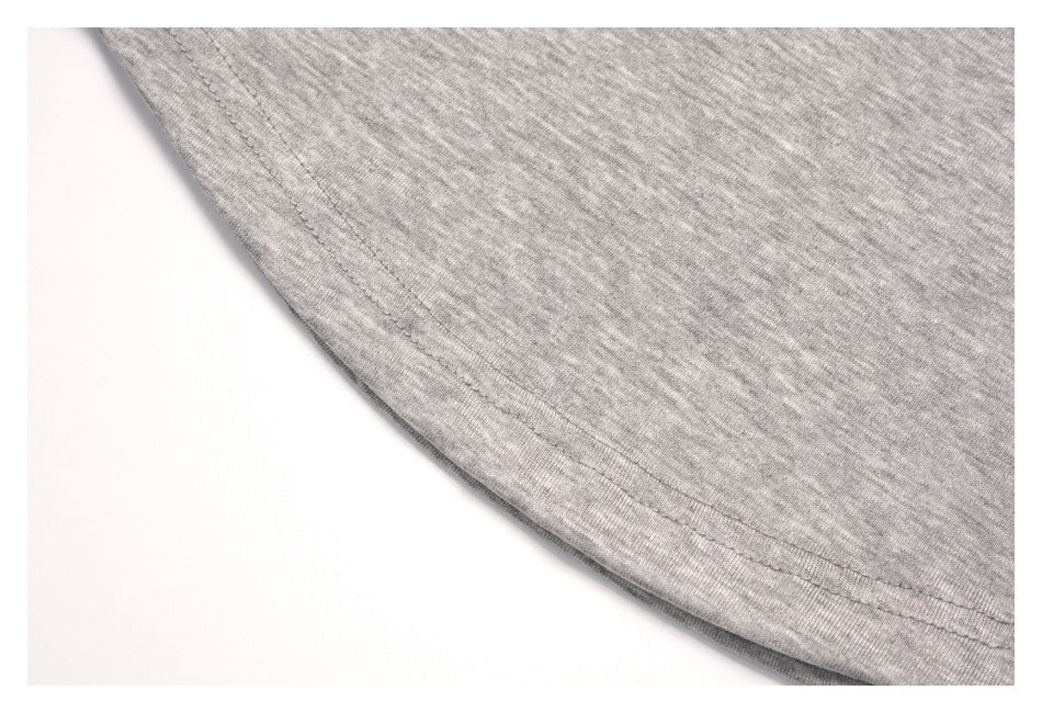 Close-up of a curved stitched edge on light gray heather fabric.