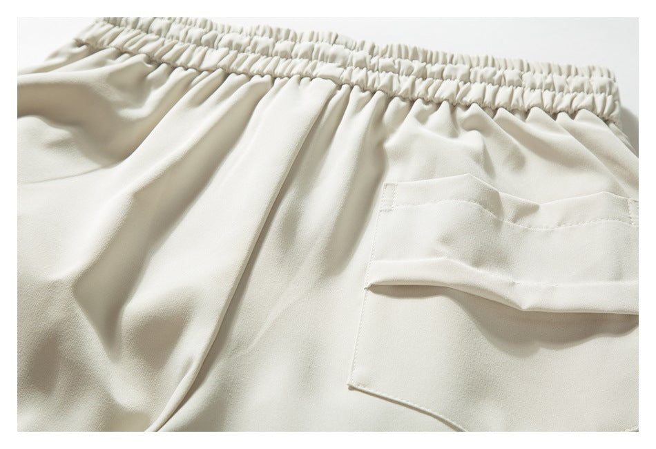 Close-up of ivory trousers showing the gathered elastic waistband and a large flap pocket.