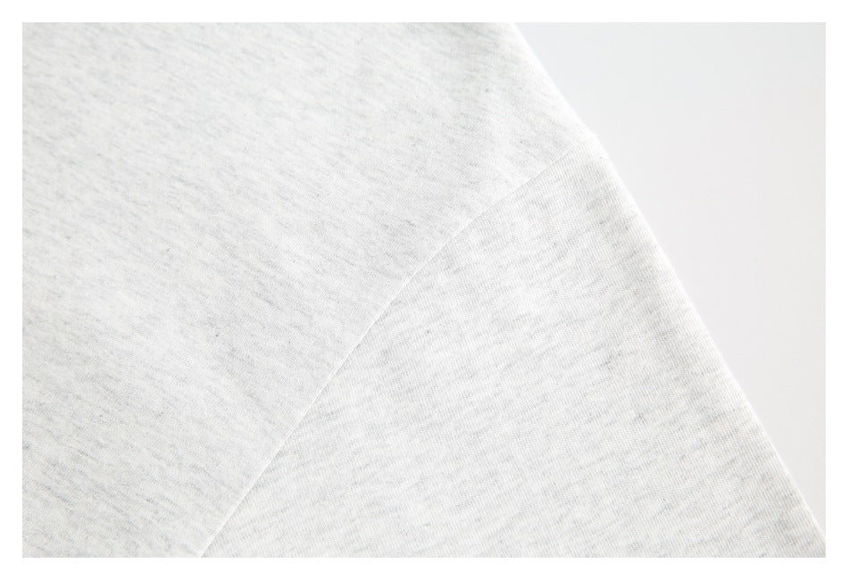 Close-up of a seam joining the shoulder and sleeve of a light gray garment.